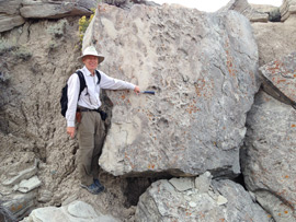 Ross Secord in Toadstool Park next to a sandstone block covered in rhino footprints